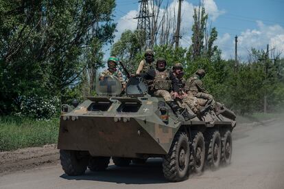 Ukrainian soldiers ride an APC on the frontline near Bakhmut