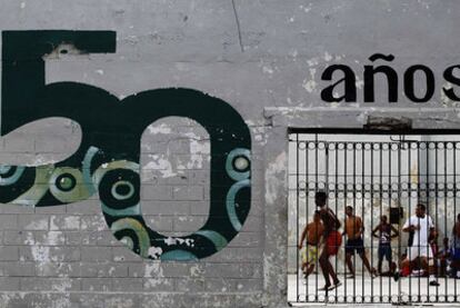 Un grupo de hombres juega al fútbol detrás de un muro con una pintada que conmemora los 50 años de la Revolución, en La Habana.