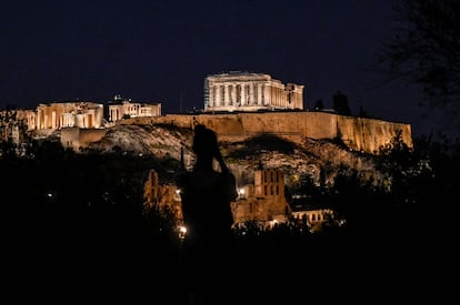 Una mujer tomaba una imagen de la Acrópolis de Atenas, iluminada, el 1 de agosto. 