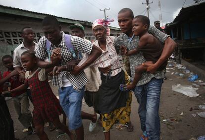 MONROVIA, LIBERIA - AUGUST 20: Family members of West Point district commissioner Miata Flowers flee the slum while being escorted by the Ebola Task Force on August 20, 2014 in Monrovia, Liberia. The military was called in to extract the commissioner and her family members from the seaside twon after residents blamed the government for setting up a holding center for suspected Ebola patients in their community. A mob overran and closed the facility on August 16. The military also began enforcing a quarrantine on West Point, a congested slum of 75,000, fearing a spread of the epidemic. The Ebola virus has killed more than 1,200 people in four African nations, more in Liberia than any other country. (Photo by John Moore/Getty Images)