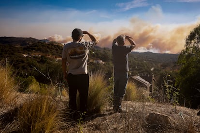 Dos vecinos de Topanga observan el incendio Palisades arde en las colinas entre Pacific Palisades y Malib, el mircoles 8.