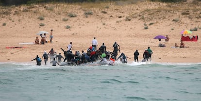 Moroccan migrants disembark from a dinghy at 