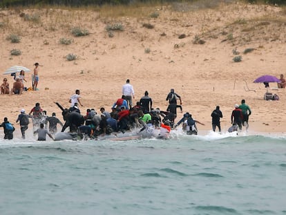 Moroccan migrants disembark from a dinghy at 