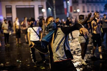 Um jovem lança uma pedra aos policiais durante os confrontos em frente ao Arco do Triunfo de Paris.