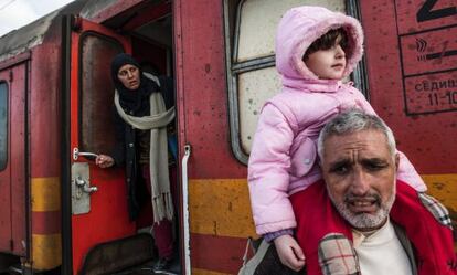 Tres migrantes esperan este miércoles en un tren para cruzar la frontera entre Grecia y Macedonia.