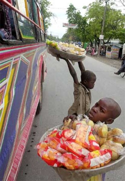 Dos niños venden comida a los pasajeros de un autobús en la ciudad haitiana de Les Cayes.