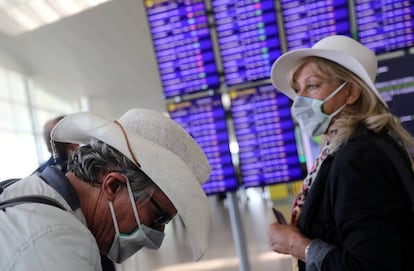 Dos viatgers amb mascaretes esperen el seu vol a l'aeroport del Prat.