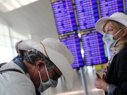 Dos viajeros con mascarillas esperan su vuelo en el aeropuerto de El Prat. 