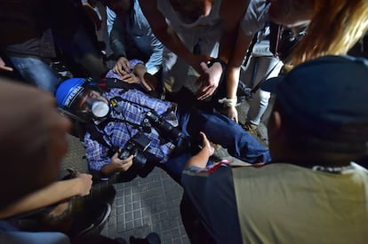 Um fotógrafo que desmaiou durante um protesto é assistido por manifestantes.