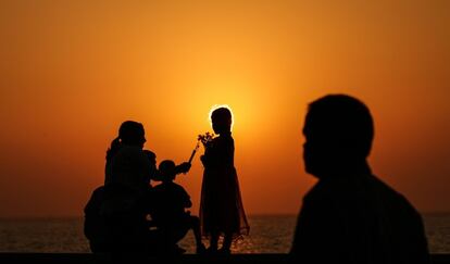 Una niña vende juguetes para hacer pompas de jabón durante el atardecer en un paseo cerca de la costa árabe de Mumbai (India).