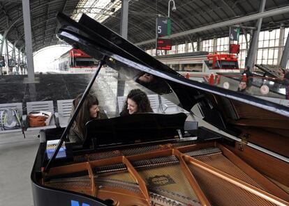 Dos jóvenes tocan el piano instalado en la estación de tren de Abando.