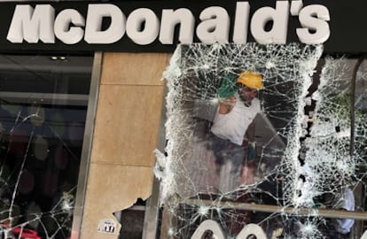 Un operario retira los cristales de una luna rota en un restaurante de comida rápida, el día después de la batalla campal entre policía y manifestantes que protestaban contra los duros recortes aprobados en el parlamento.