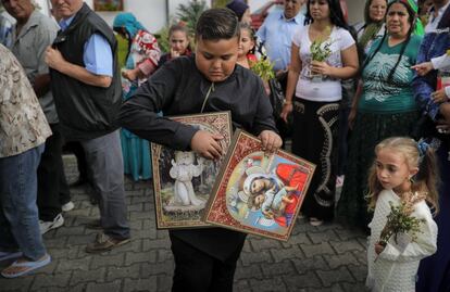 Hoy en día, siguen siendo discriminados de forma habitual en el país, por lo que suelen tener dificultades para integrarse en la sociedad. En la imagen, un joven perteneciente a la etnia gitana de Rumanía sujeta iconos religiosos, mientras hace cola para tocar los restos de un santo, en una iglesia de Costesti.