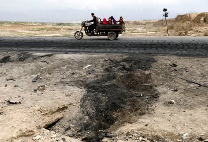 Una familia afgana pasa junto al sitio de un ataque con coche bomba contra la base aérea estadounidense de Bagram (Afganistán). 