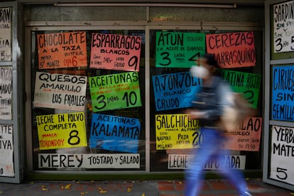 Una mujer camina frente a carteles que muestran los precios de los productos en dólares estadounidenses, afuera de una tienda de comestibles en Caracas (Venezuela).