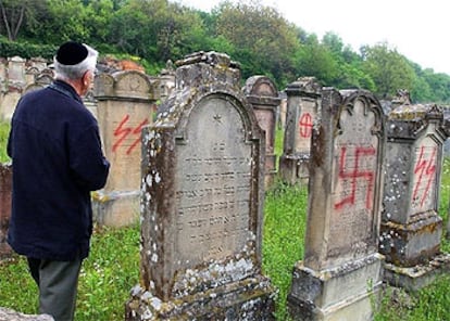 Un hombre  observa el estado de algunas lápidas del cementerio de Herrlisheim, pintadas con signos nazis.