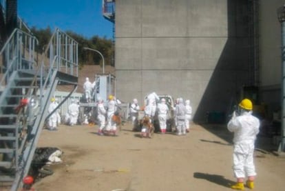 Fotografía facilitada por la empresa operadora de la central nuclear de Fukushima Daiichi, TEPCO, que muestra a sus trabajadores vestidos con monos especiales mientras trabajan en reestablecer el tendido eléctrico en los reactors 3 y 4 de la planta, en Okumamachi, en la prefectura de Fukushima (Japón).