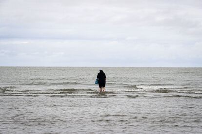 Una mujer hace un ritual en la playa Ramírez, en Montevideo (Uruguay). La pandemia de la covid-19 obligó a que la tradicional celebración de la diosa de las aguas Iemanjá en las costas de Uruguay cambiara su escenario este martes por una acción solidaria en la que sus fieles donaron alimentos para las ollas populares que reparten comidas a las personas con mayores carencias.