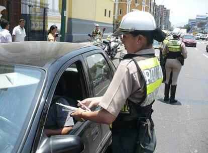 Una mujer policía impone una multa a un conductor en una calle de Lima.