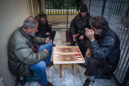 Varios hombres juegan al backgammon cobijados de la lluvia en el Pireo.