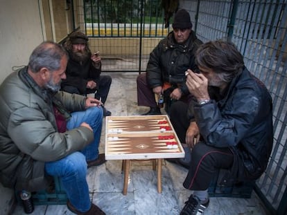 Varios hombres juegan al backgammon cobijados de la lluvia en el Pireo.