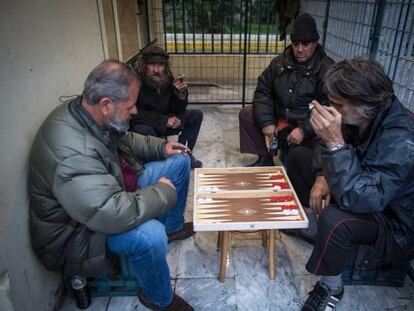 Varios hombres juegan al backgammon cobijados de la lluvia en el Pireo.