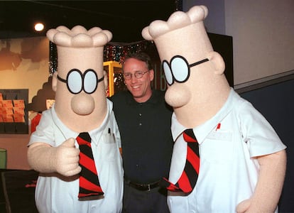 Scott Adams, the creator of "Dilbert", the cartoon character that lampoons the absurdities of corporate life, poses with two "Dilbert" characters at a party January 8, 1999 in Pasadena, Calif.