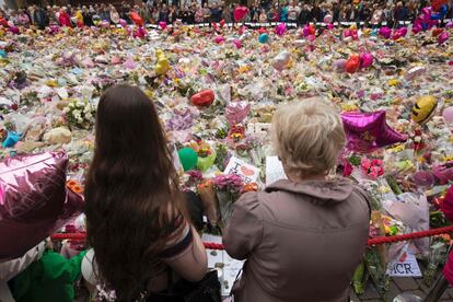 Varias personas miran las flores depositadas en la plaza Santa Ana de Manchester (Inglaterra) en homenaje a las víctimas del ataque terrorista del pasado 22 de mayo. 