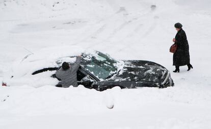 Un hombre retira la nieve amontonada del techo de su vehículo después de una nevada en Moscú (Rusia), el 13 de febrero.