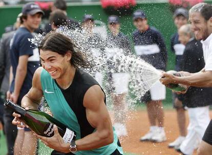 Rafael Nadal, con su propia botella aún sin abrir, trata de esquivar las burbujas de cava que le lanza Guillermo Cañas.