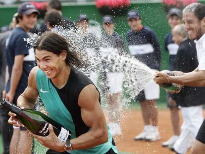 Rafael Nadal, con su propia botella aún sin abrir, trata de esquivar las burbujas de cava que le lanza Guillermo Cañas.