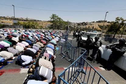 Miembros de la policía israelí permanecen vigilando a palestinos que realizan las oraciones del viernes, en las afueras de Jerusalén (Israel).