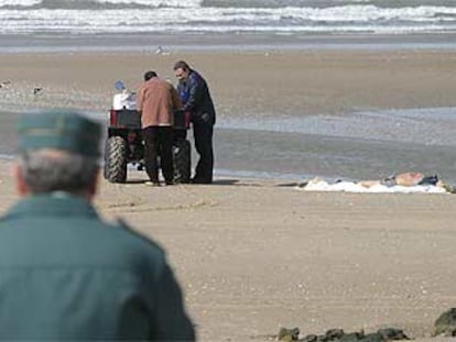 Un guardia civil observa el levantamiento de cadáveres en la playa de Rota.