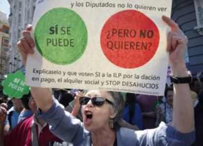 Una mujer sostiene una pancarta durante la concentración convocada por la Plataforma de Afectados por la Hipoteca (PAH) frente al Congreso, el día en el que se aprobó el proyecto de Ley de Protección de los Deudores Hipotecarios. EFE/Archivo