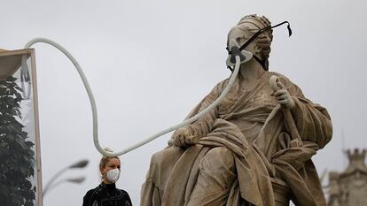 Activistas de Greenpeace colocan una mascarilla a la Cibeles.