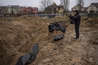 Un periodista toma imágenes de una fosa común en Bucha, el domingo. El presidente francés, Emmanuel Macron, ha respondido a las imágenes de cadáveres en las calles de Bucha, una localidad a 25 kilómetros del centro de Kiev, donde, según Ucrania, las fuerzas rusas han ejecutado a cientos de civiles. "Las imágenes que nos llegan son inaguantables", ha afirmado el domingo a través de su cuenta de Twitter.