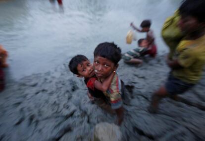 Dos hermanos refugiados rohingya, atrapados en el lodo después de cruzar el río Naf en la frontera entre Bangladés y Myanmar en Palong Khali.