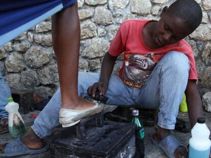 Un ni&ntilde;o saca brillo a los zapatos de una mujer en Puerto Pr&iacute;ncipe, Hait&iacute;. 