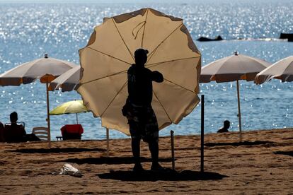 Un trabajador instala las sombrilas y hamacas en la playa de la Barceloneta, que ha permanecido cerrada toda la noche para evitar concentraciones con motivo de la verbena de San Juan.