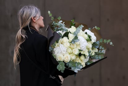 El velatorio esta marcado por flores completamente blancas, el color elegido para rendir homenaje al diseñador.  En la imagen, una mujer lleva flores a la capilla ardiente, este sábado. 