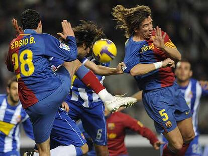 Sergio Busquets y Puyol intentan despejar ante Román.