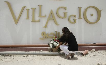 Una mujer deposita un ramo de flores en la fachada del centro Villaggio Mall.