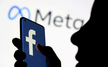 Una mujer sostiene un teléfono inteligente con el logo de Facebook