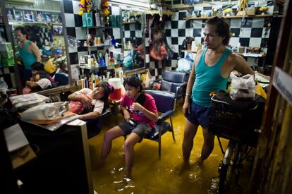 Una familia ve la televisión en un salón de belleza inundado por las lluvias