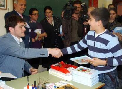 Casillas entrega un ejemplar de <i>La magia de Iker</i> a un alumno.