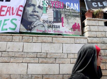 Una mujer pasa ante un cartel que pide a Obama que intervenga para frenar los asentamientos en Jerusalén Este.