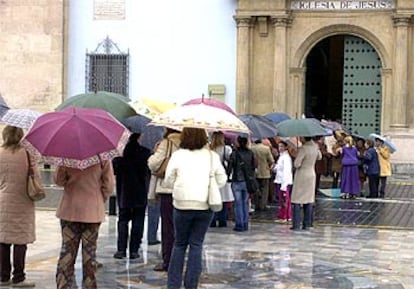 Cientos de personas hacen cola bajo la lluvia ante la iglesia de Jesús para ver las imágenes, talladas por Francisco Salzillo, que debían haber procesionado por las calles de Murcia en el desfile de la Real y Muy Ilustre Cofradía de Nuestro Padre Jesús Nazareno suspendido a causa del mal tiempo.