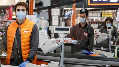 Un joven posa en la caja del supermercado en el que trabaja en Madrid.