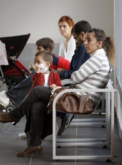 Un niño con mascarilla junto a su familia en el nuevo centro de salud Barrio del Puerto.