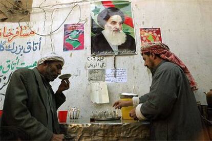 Dos iraquíes toman el té en un establecimiento de Nayaf bajo un retrato del gran ayatolá Alí al Sistani.